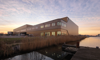 Het gebouw (Waalwijk DCII) aan water met een stijger in de voorgrond